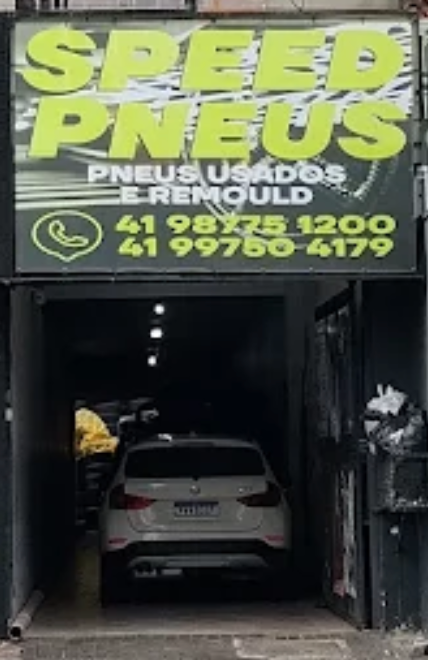 Fachada da Speed Pneus: letreiro preto com verde-limão e os telefones da loja